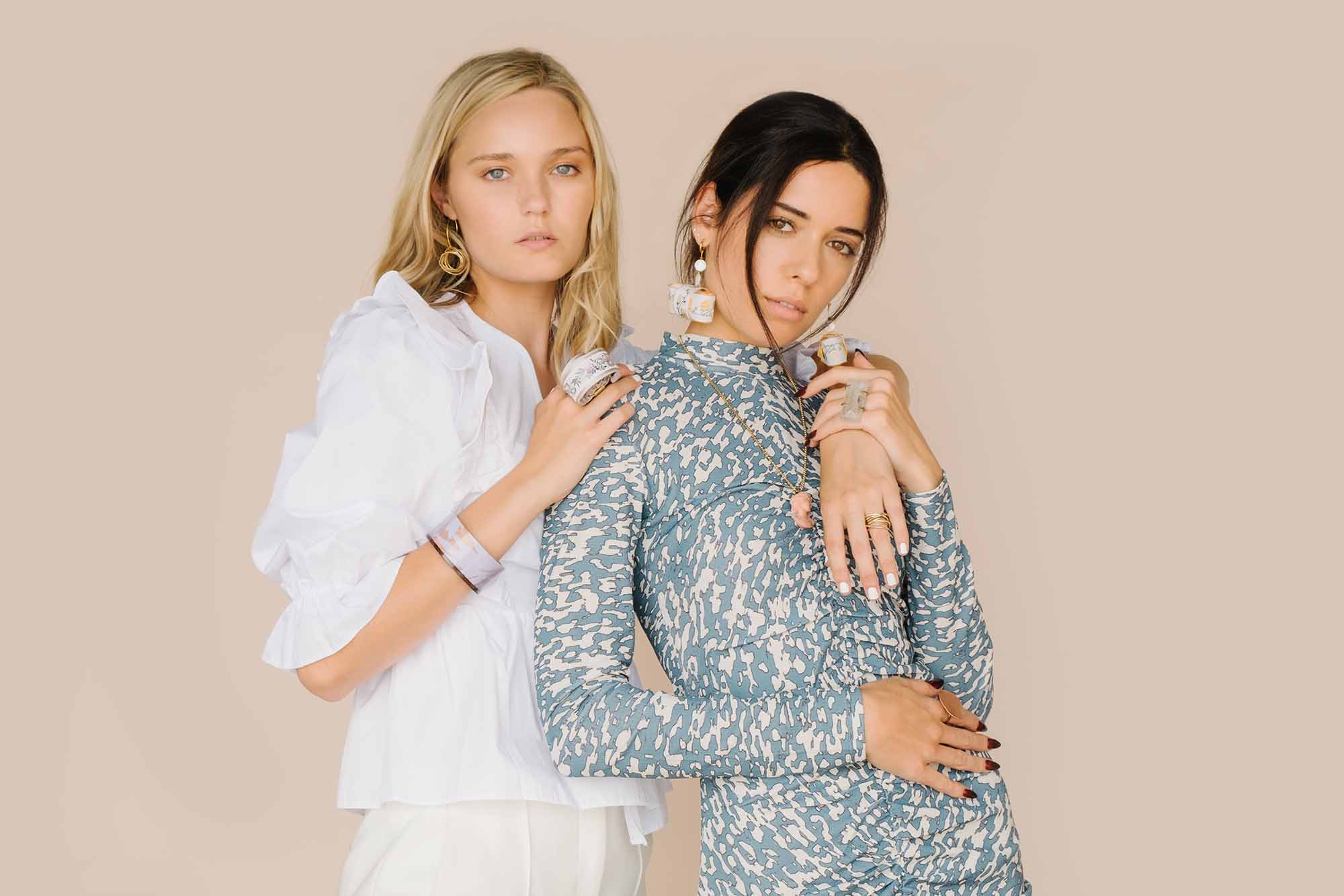 Two models showcasing contemporary fashion styles against a neutral backdrop, adorned with statement jewelry.