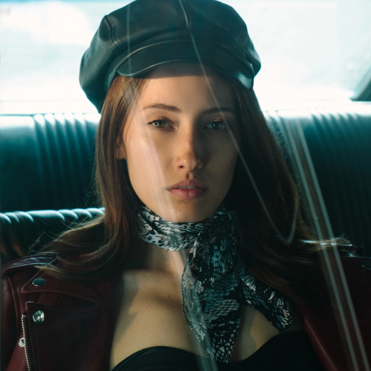 Stylish woman in a red leather jacket and black beret, accented with a patterned scarf, giving a contemplative gaze in a vintage setting with soft lighting — A Los Angeles photography studio portfolio
